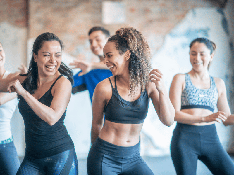 Jovens na sala de dança fazendo dança aeróbica e sorrindo