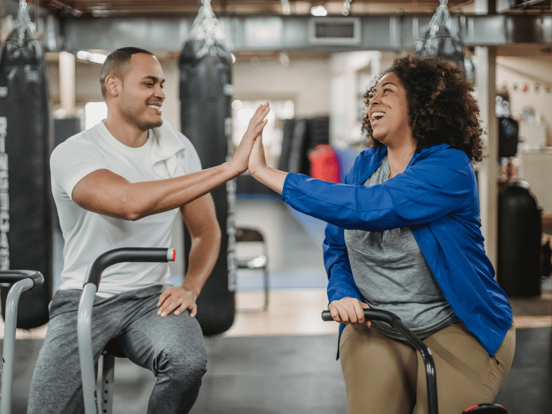 Pessoas fazendo High Five numa academia - Two people high fiving at a gym - Entenda o lado psicológico do seu cliente