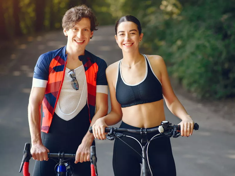 Jovem homem e mulher com bicicletas sorrindo.